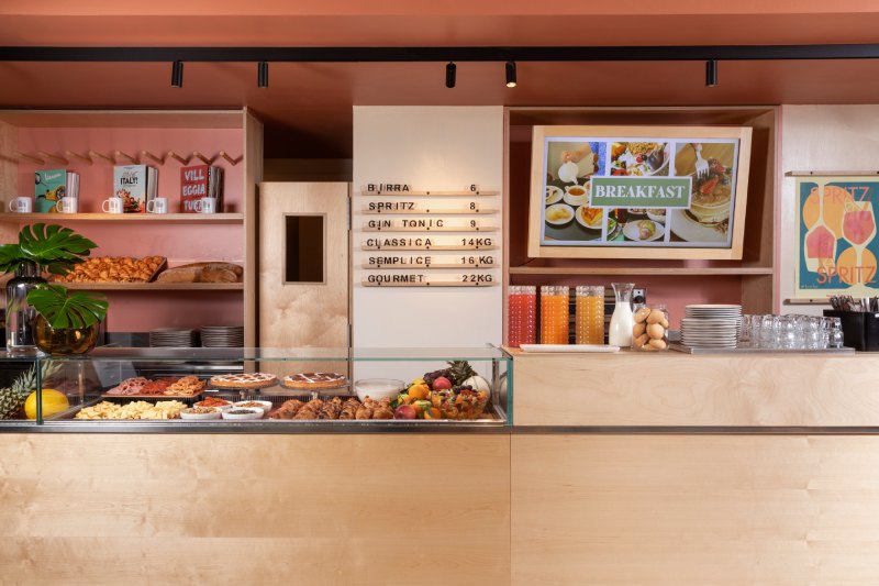 Spazio bakery e cucina dell’hotel con tavoli interni e vista sull’area bar per colazioni e snack a Roma - Moderno Hotel Roma, BZAR hotels a Roma
